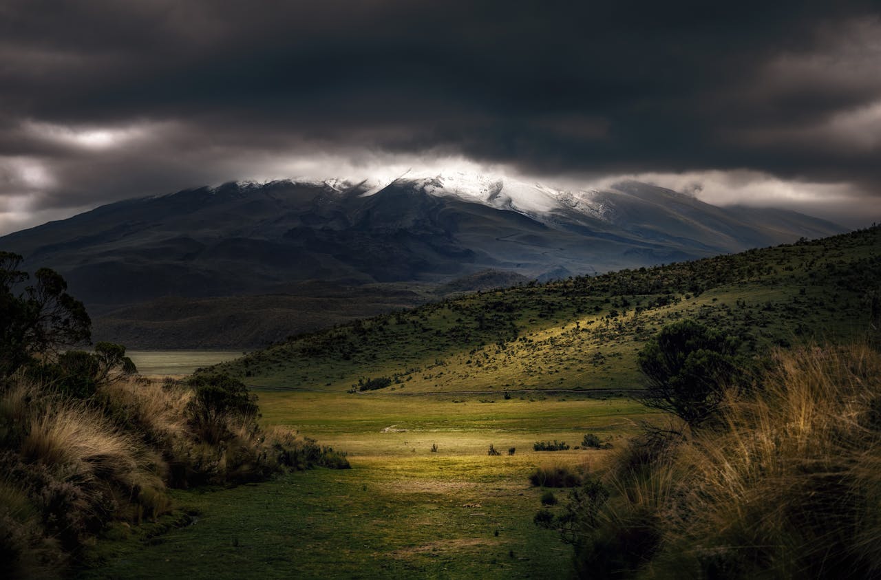 Stunning mountain landscape with dramatic dark clouds and green terrain.