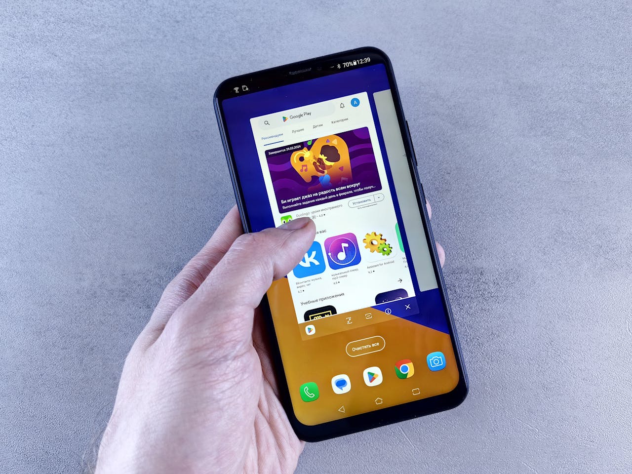service-01 Close-up of a hand holding a smartphone displaying an app store interface on a gray background.